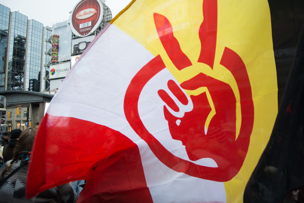 A demonstrator waves a flag during an Idle No More protest on January 11, 2013 at Yonge Dundas Square in Toronto.