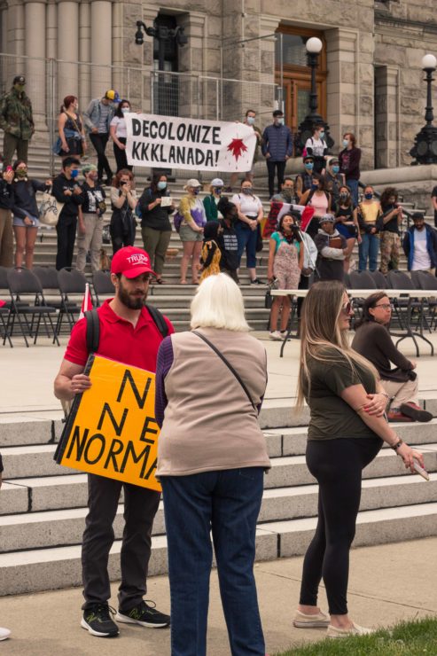 A person wearing a trump hat stands in front of the Resist Canada 153 group