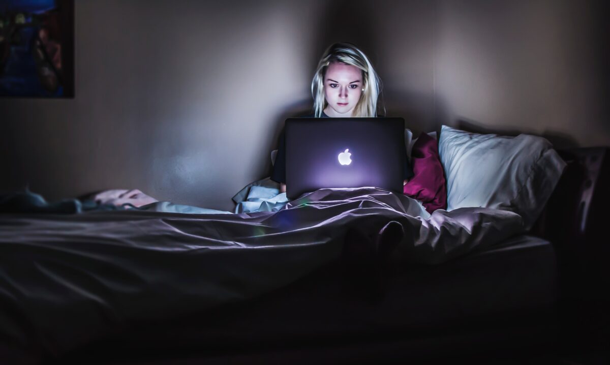 Woman at a laptop in the dark. Photo by Victoria Heath via Unsplash.