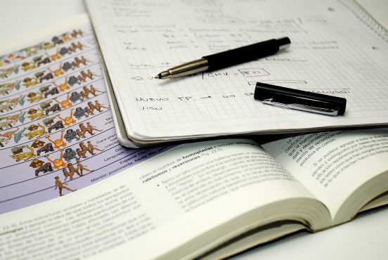 Biology exam textbooks and notes, photo by Paula Bessi via pixabay.