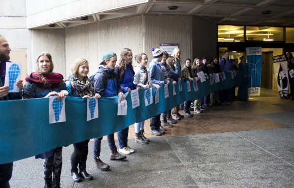 Students hold a blue banner representing investment in clean energy sources. Photo by Cormac O'Brien