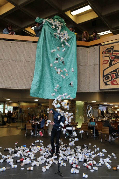 Levi Hildebrand has used coffee cups dumped on him in the University Centre to draw attention to the number of cups thrown out on campus every day. Photo by Belle White, Photo Editor