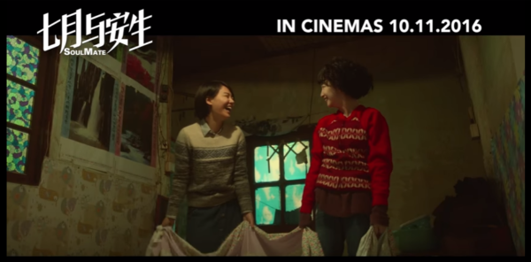 Screenshot of SoulMate trailer, shows two women in a room with a bedsheet and lists the date the movie will be available in theatres. 