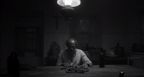 An elderly man sits at the centre frame wiith a rope in the trailer for The Little Girl Who Was Too Fond of Matches
