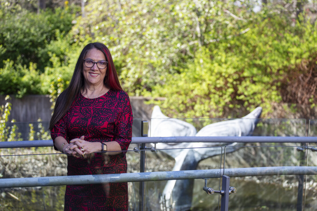 UVic’s first Associate Vice President, Indigenous, Qwul’sih’yah’maht Robina Thomas, at the First Peoples House reflecting pool. Bronze sculpture "Gray Whale Tail" by Calvin Hunt (Kwakwaka'wakw) and John Livingston. (Photo credit: UVic, April 2021)