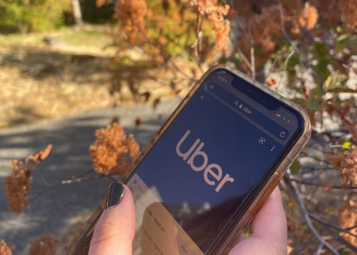 Person holding a phone with the Uber app open, photo by karley Sider.