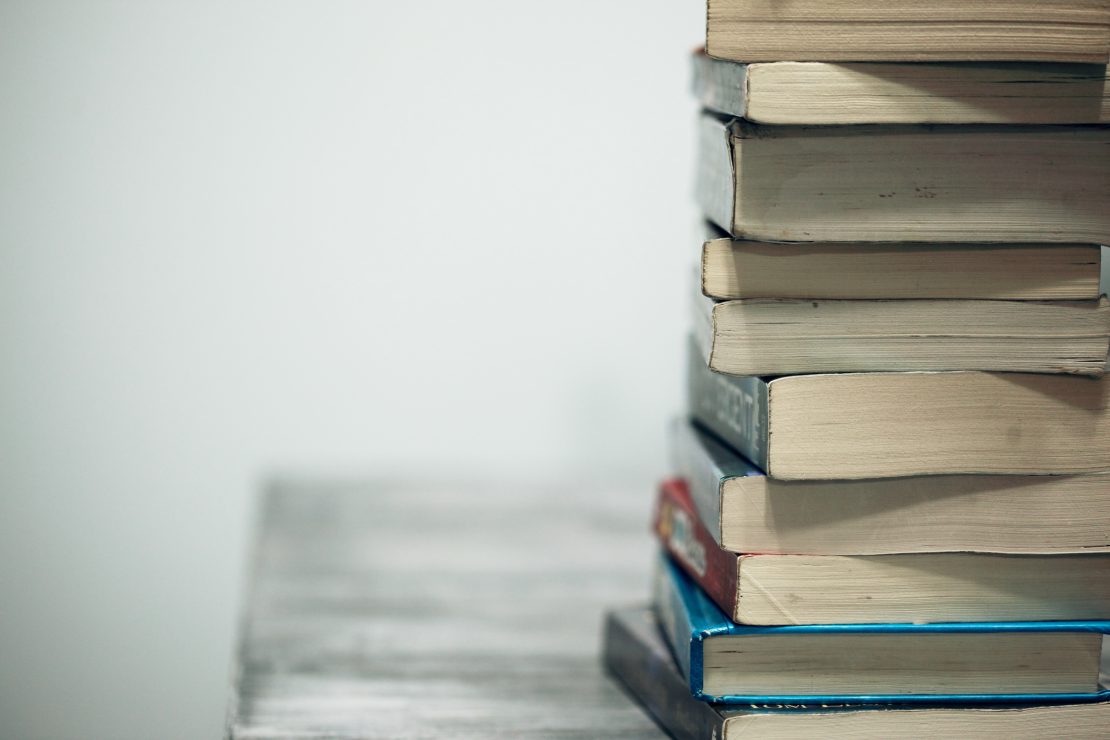 A stack of books, photo by Alexander Grey via Unsplash.